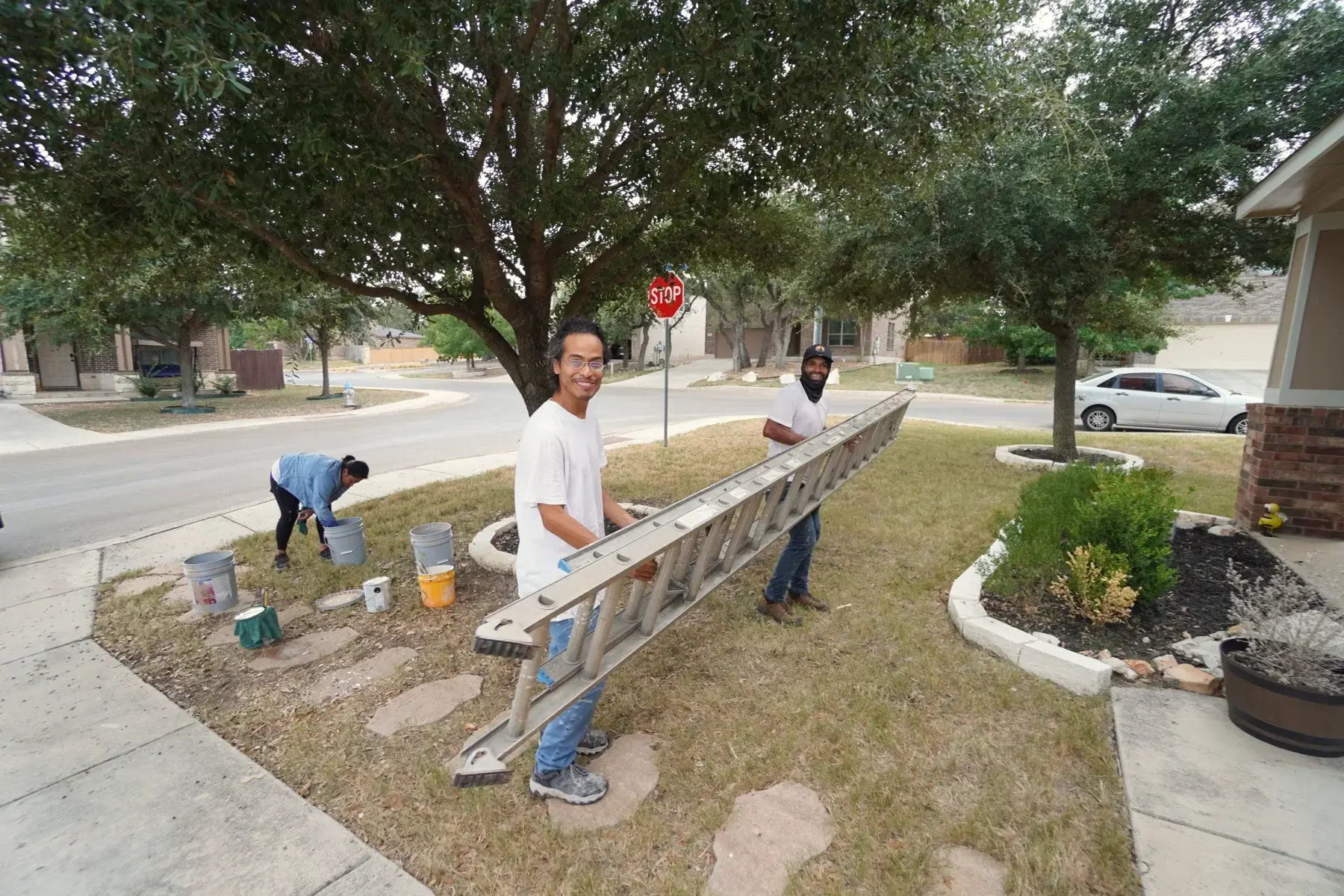 A.C.L. Painting crew carrying an extension ladder toward the house during project setup