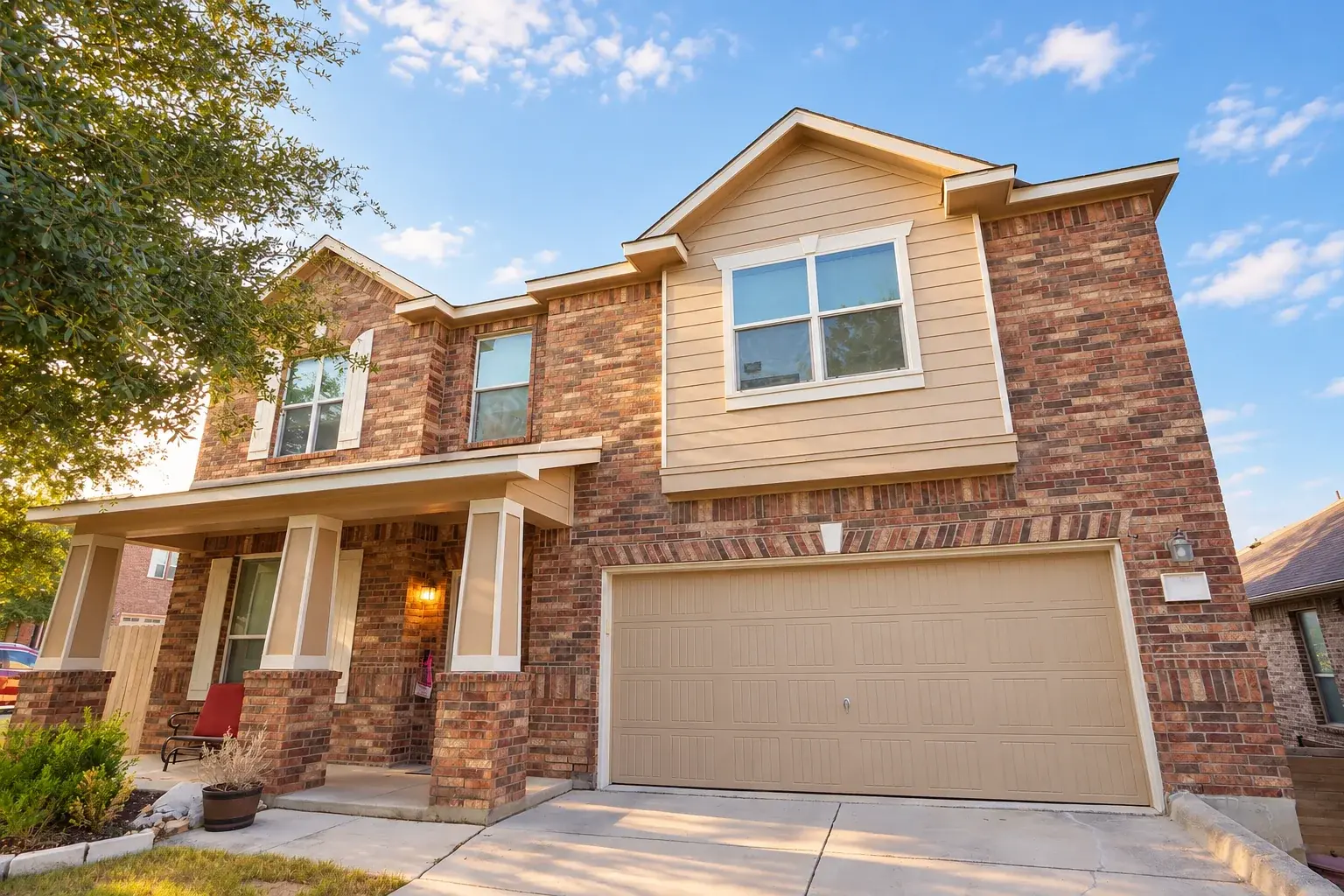 Finished brick home with freshly painted garage door, gable, porch columns, and white trim
