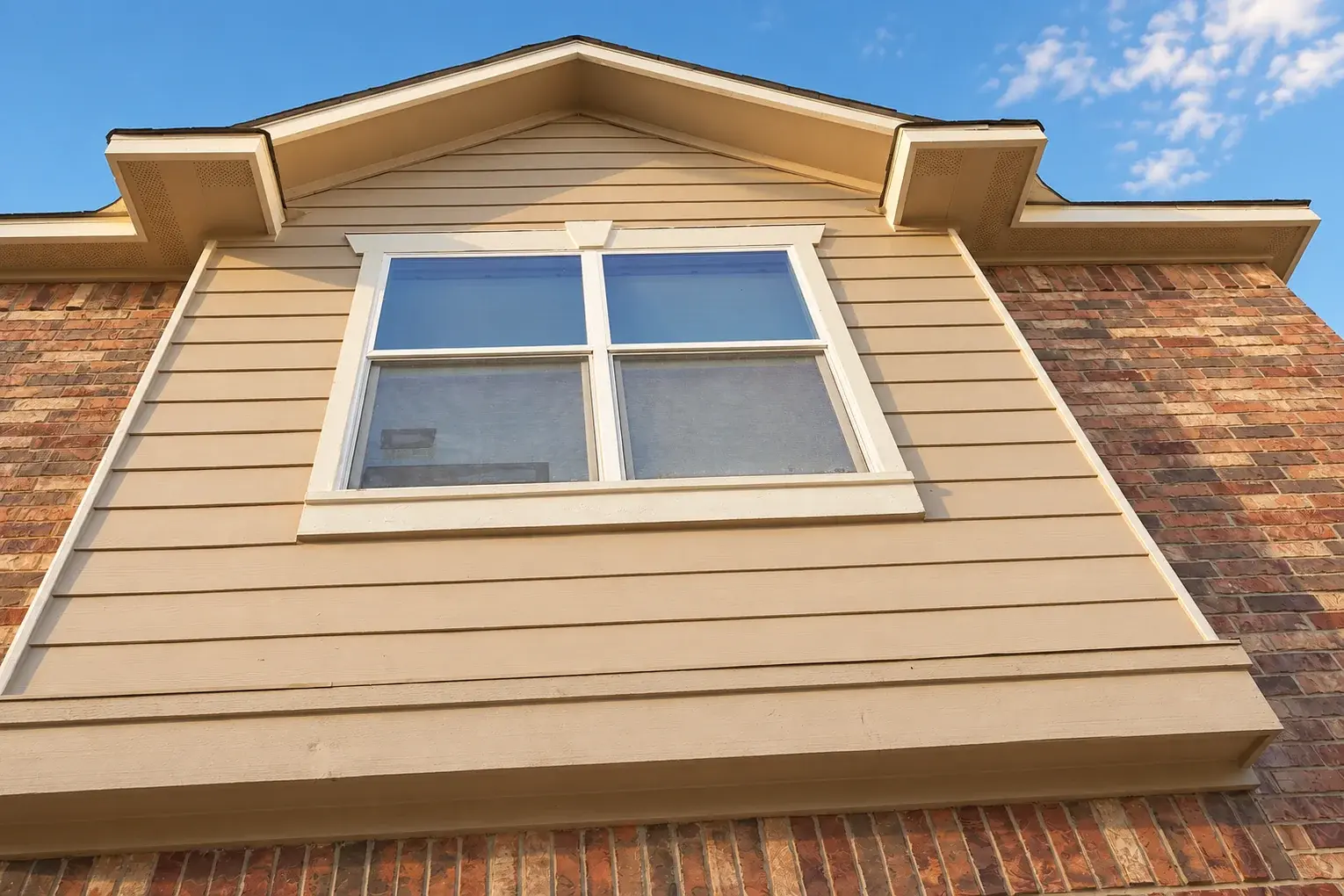 The same garage gable with freshly painted siding, white window trim, and finished fascia