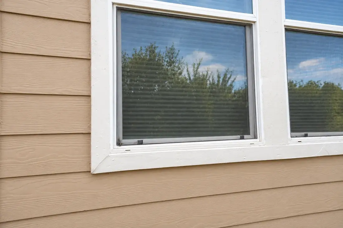 Finished white trim at the lower left window corner after wood repair and painting