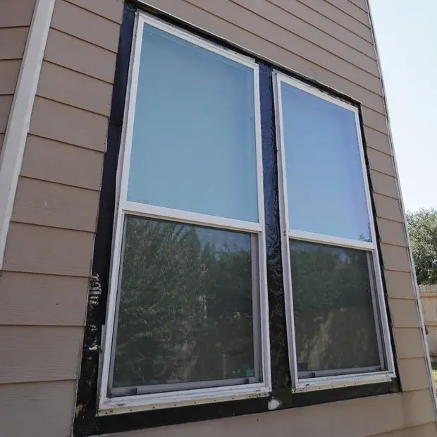 Rear double windows during repair, with old trim removed and dark flashing exposed